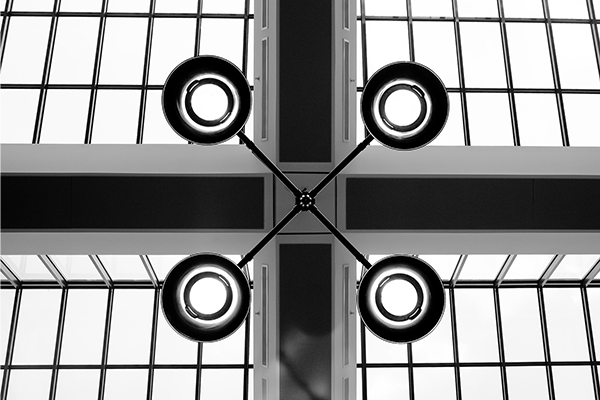 Black and white image showing a center lamp post with four circular lights around the center.  